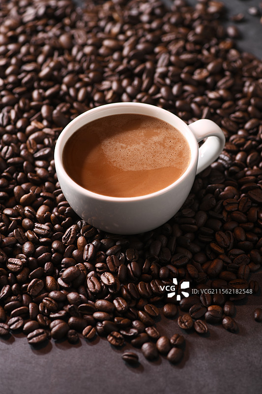 一杯卡布奇诺咖啡，周围铺满了咖啡豆图片素材