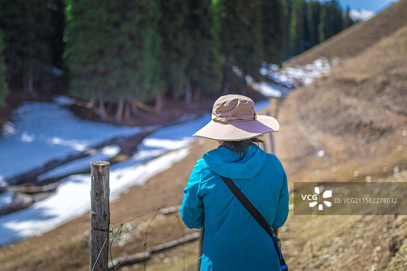 春天 蓝色冲锋衣的亚洲美女 在雪山草原 徒步爬山探险图片素材