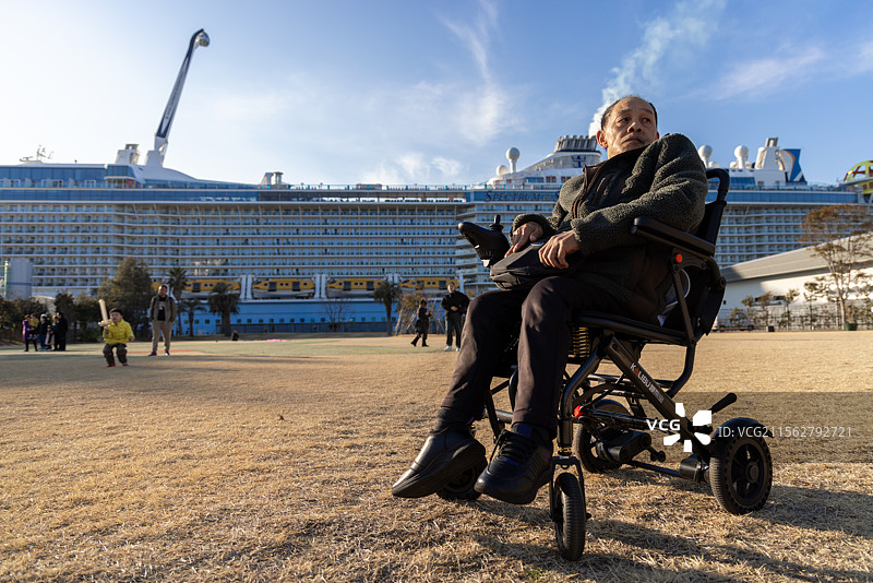 中国轮椅残疾老人与停靠在日本九州地区熊本八代港的海洋光谱号邮轮合影打卡图片素材