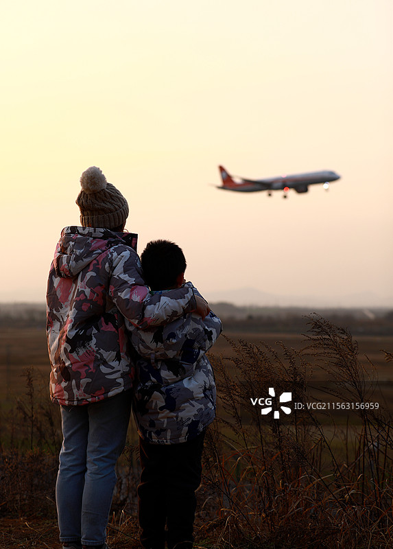 妈妈带着孩子看飞机降落图片素材