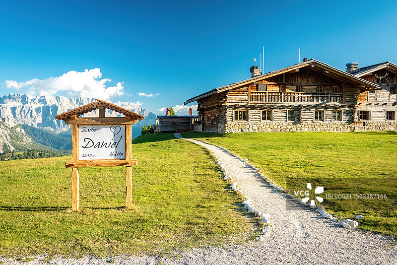 意大利多诺米蒂白云岩山间木屋风光，蓝天白云映衬下，绿草地上的木制小屋与周围环境和谐相融图片素材