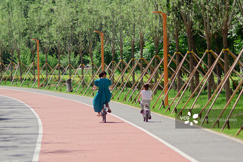 母亲和女儿骑自行车的后视图，城市户外自然，母亲节儿童节，亲子成长童年，夏天户外母女背影图片素材