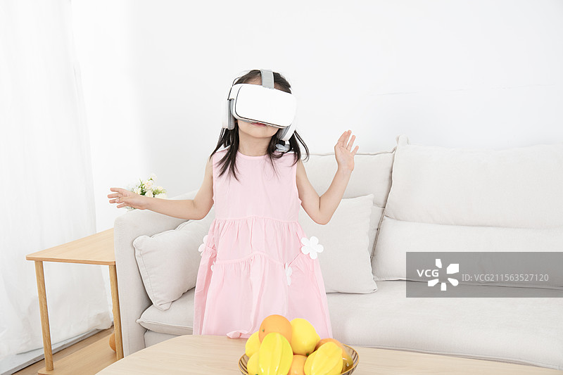 头戴VR的小女孩坐在沙发上图片素材