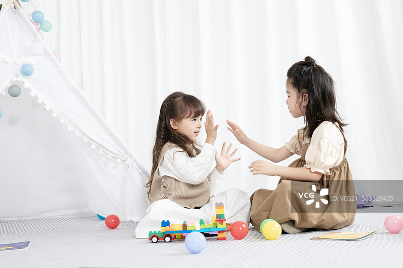 玩击掌游戏的两个小女孩在房间里开心的玩耍图片素材