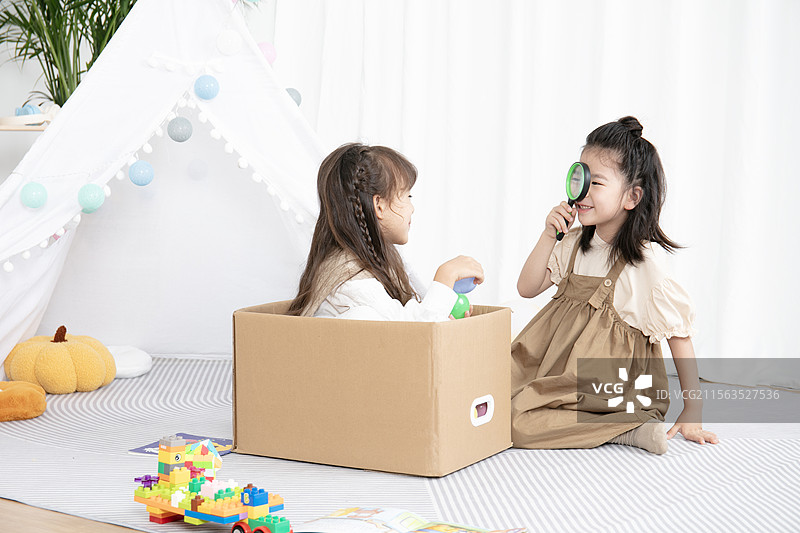 两个小女孩利用包装盒在房间里开心的玩耍图片素材