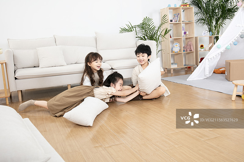 三个小朋友在沙发上进行枕头大战图片素材