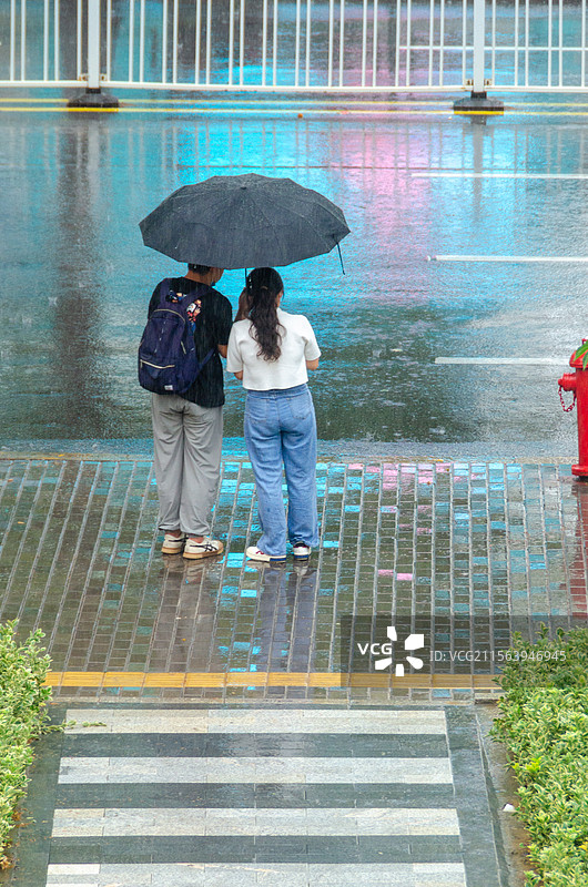 雨中在马路边等车的一对男女图片素材