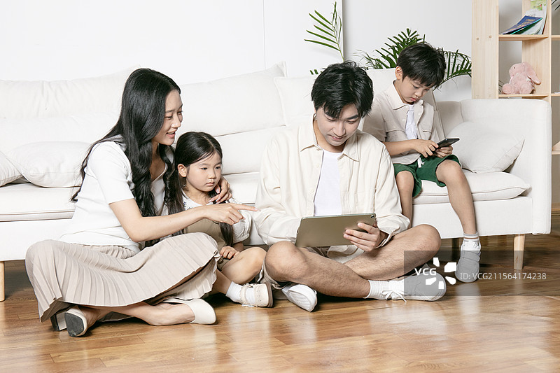 一家四口坐在地板上使用平板电脑图片素材