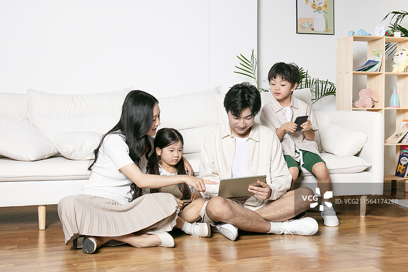 一家四口坐在地板上使用平板电脑图片素材