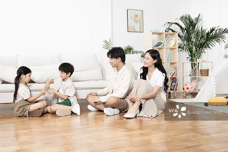 坐在地板上玩石头剪刀布的一家四口图片素材