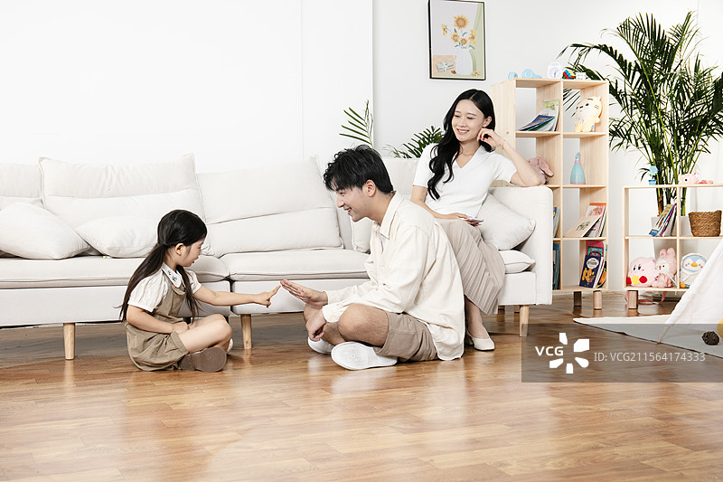 坐在地板上玩石头剪刀布的一家三口图片素材
