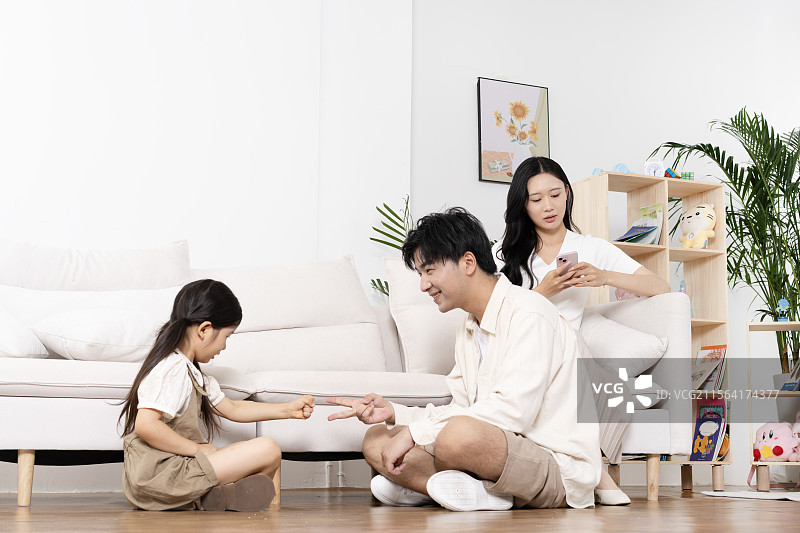 坐在地板上玩石头剪刀布的一家三口图片素材