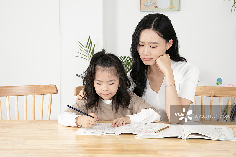 辅导女儿写作业的年轻妈妈图片素材