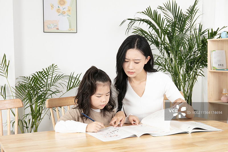 辅导女儿写作业的年轻妈妈图片素材