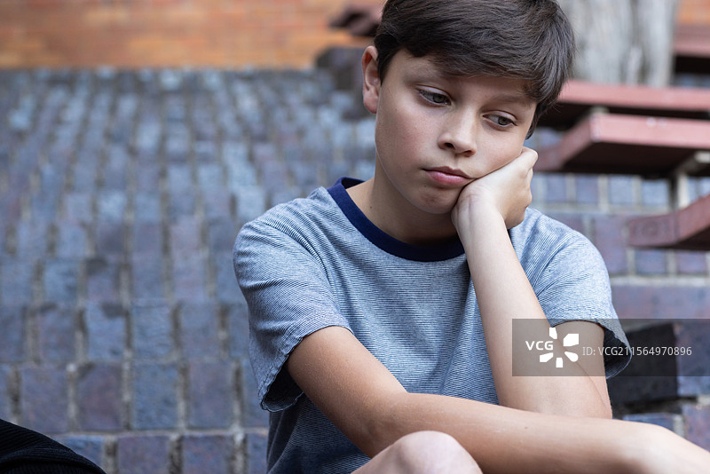 坐在台阶上的男孩，放学后显得沉思和忧虑图片素材