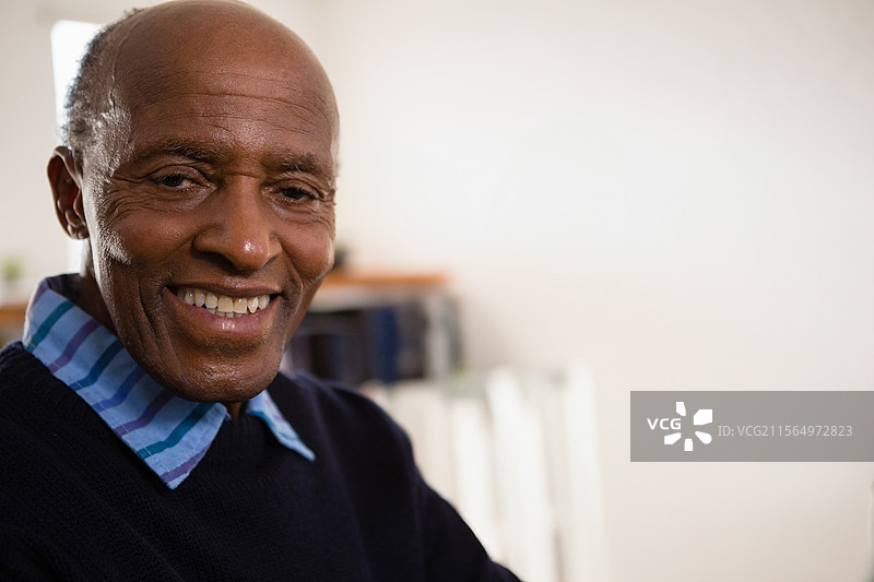 坐在办公室里的非裔美国老人微笑，书架和阳光映衬，留有空白空间图片素材