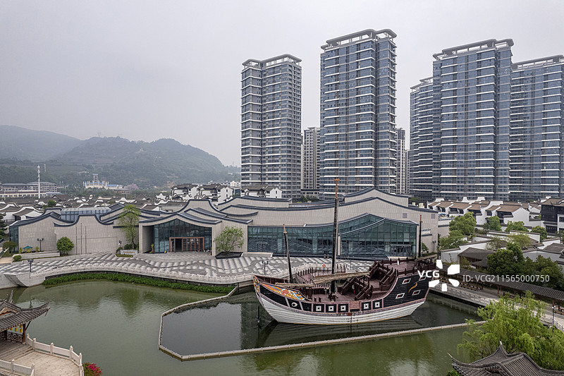 福建闽越水镇里的福船模型、传统闽派建筑与城市天际线图片素材