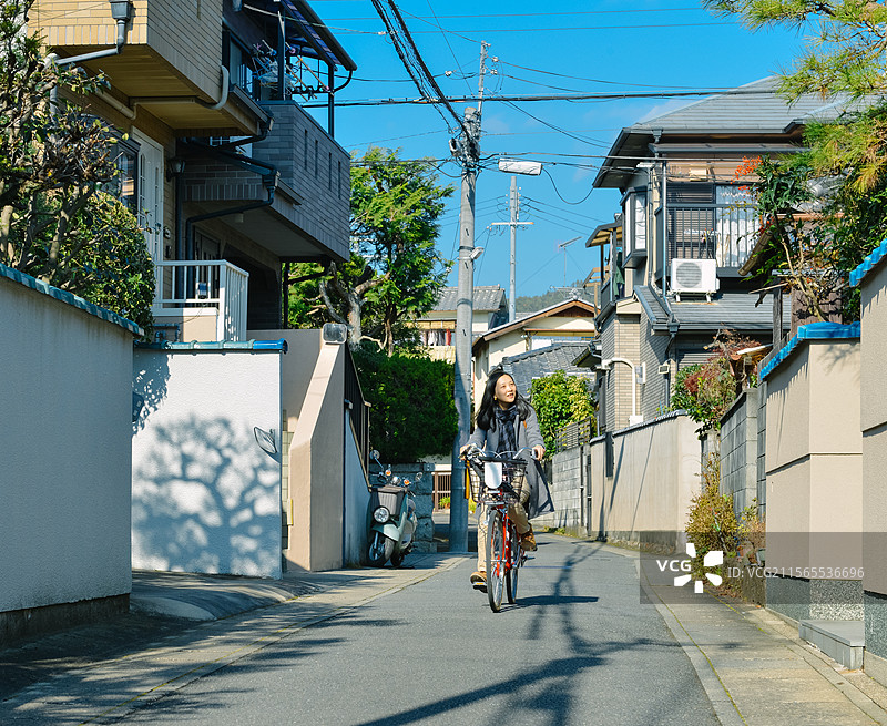 一位女性骑着自行车在日本京都城市街道中旅行图片素材