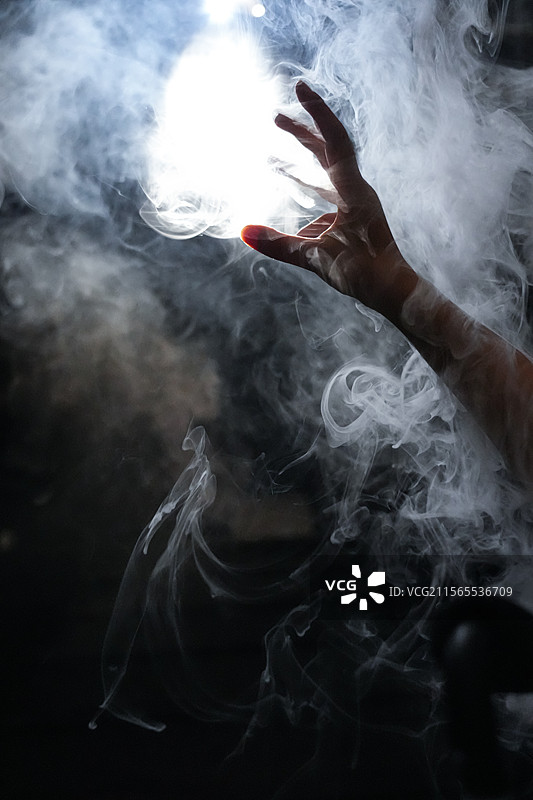 烟雾缭绕中，一只手企图握住光芒图片素材