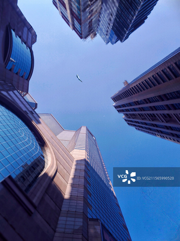 铜锣湾上空的蔚蓝航迹5月2号在香港铜锣湾游玩。下午5点左右，天气睛好，低角度仰拍的建筑与飞机。图片素材