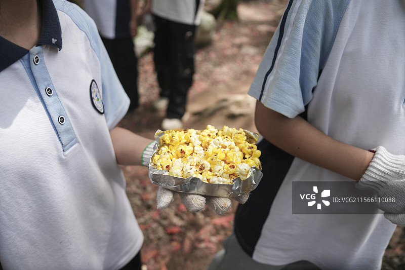 站在室外拿着爆米花的人的中间部分图片素材