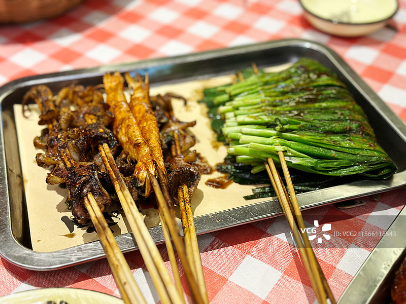 地摊经济夜市美食夜宵烧烤烤串背景桌上盘子里食物的特写镜头图片素材