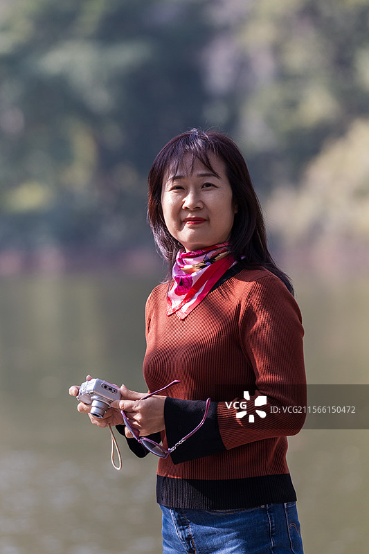 冬天公园拿着相机拍照的时尚女人图片素材