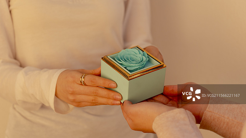手捧绿色装饰有花朵的礼物盒送给别人接收图片素材