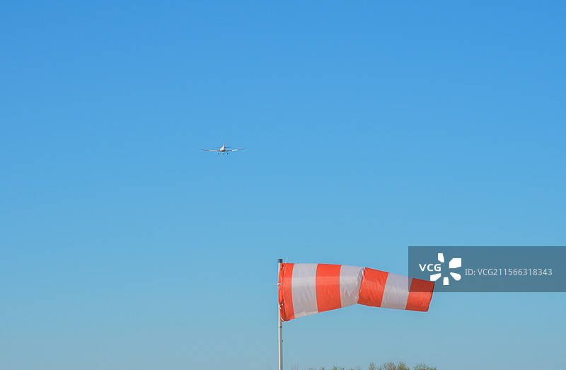被风吹起的风向袋和空中远去的轻型飞机图片素材
