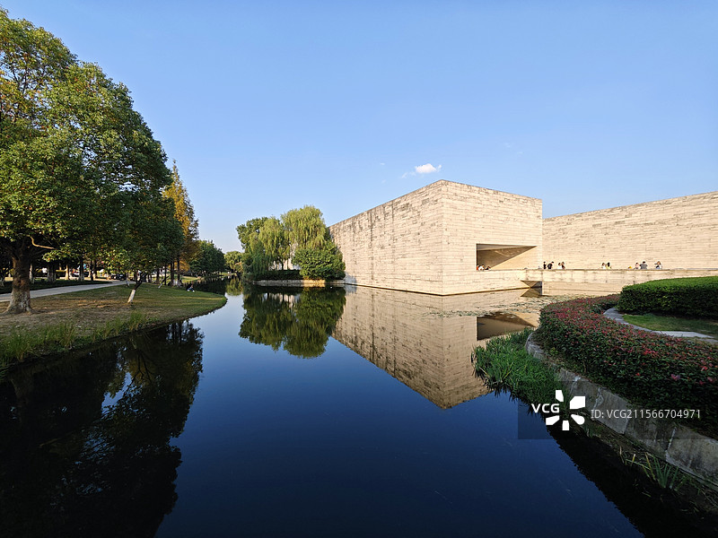 杭州市余杭区良渚美丽洲公园眺望水岸边的良渚博物院及湖面风光水平如镜图片素材