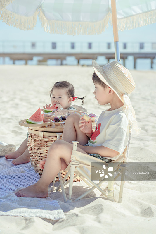 海滩露营享受美食的小男孩与妹妹图片素材