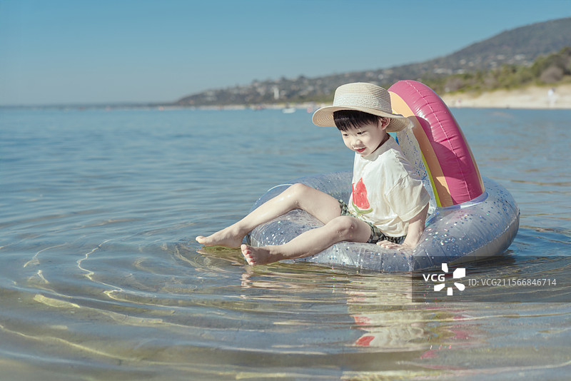 海水中玩儿童气垫皮艇的小男孩图片素材