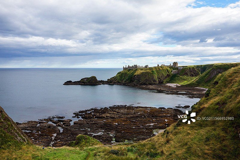 英国苏格兰东海岸边蔚蓝色的海湾风光和远处的城堡遗迹图片素材