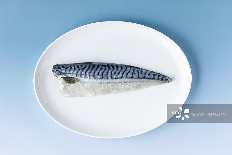 正上方蓝色背景下盘子里的青花鱼图片素材