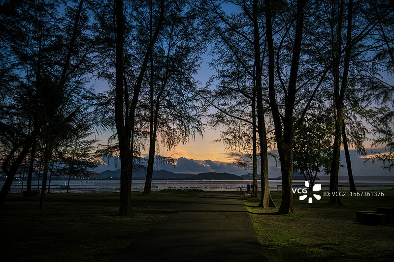 普吉岛日出时，当地的一个小公园，是观赏日出的最佳地点之一，走过被树木簇拥的小径，直达海上第一类阳光图片素材