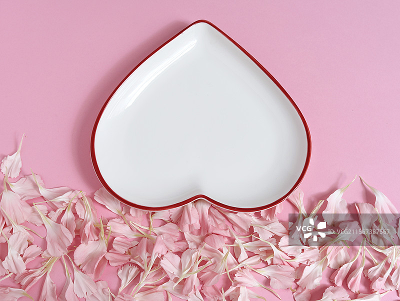 粉色背景上的情人节粉色花瓣和空白的空盘子背景图图片素材