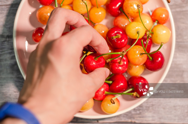 手从果盘中抓取樱桃图片素材