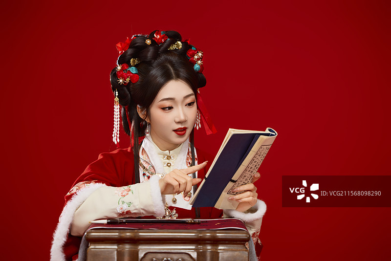 红色背景下身穿喜庆汉服认真学习的中国美女图片素材