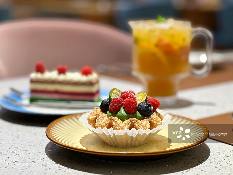 大理石桌子上法式开心果酥皮水果蛋挞和树莓芝士慕斯蛋糕搭配百香果水果茶下午茶套餐特写背景图片素材