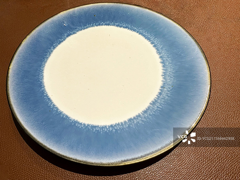 皮革背景上一个盘色圆形空的盘子背景图片素材