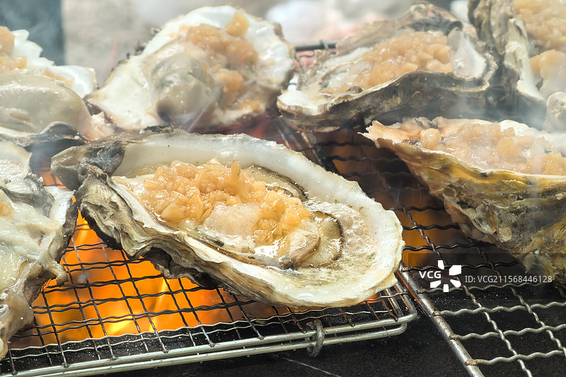 炭烤蒜蓉生蚝的特写，通红的炭火炙烤着掰开的生蚝滋滋冒油图片素材