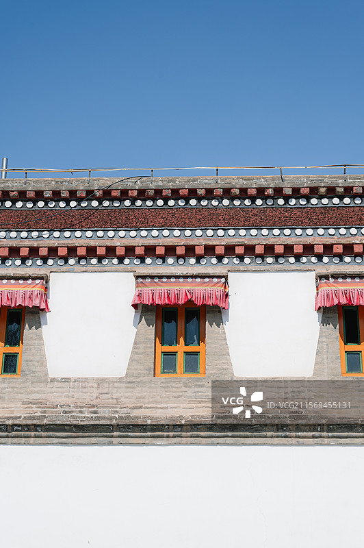 青海西宁塔尔寺特写仰拍​​窗棂几何｜红帘垂坠与石砌肌理的秩序美学​​图片素材