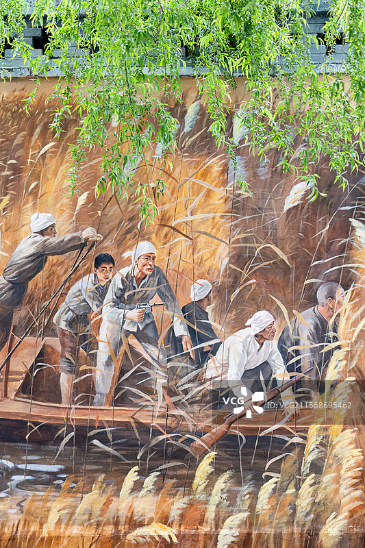 河北省雄安市白洋淀嘎子村村头墙上柳树掩映的雁翎队壁画图片素材