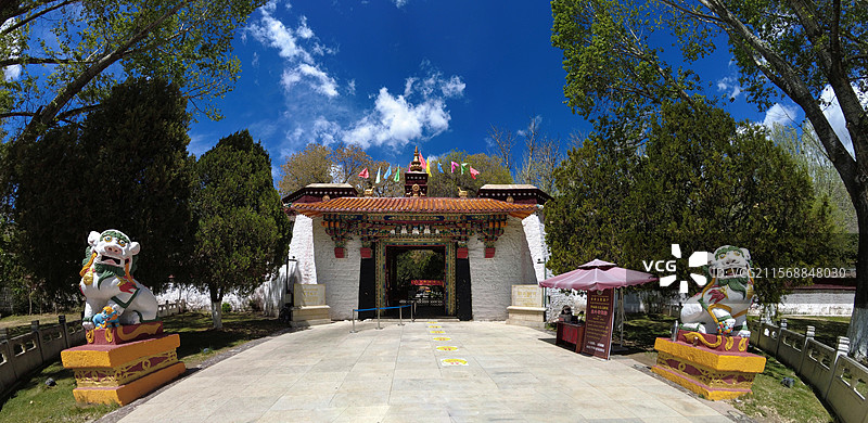 罗布林卡大门古朴庄重，色彩鲜明，饰有精美图案，周围绿树环绕，洋溢着藏式园林的独特韵味与宁静氛围。图片素材