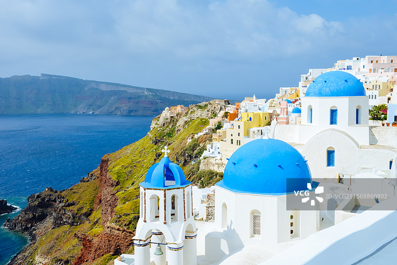 希腊圣托里尼岛伊亚镇的典型的蓝白房子、圆顶教堂与悬崖风景图片素材