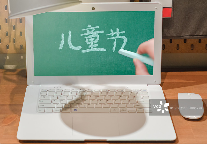 书桌的的笔记本电脑屏幕上，在黑板上写下儿童节的粉笔字图片素材