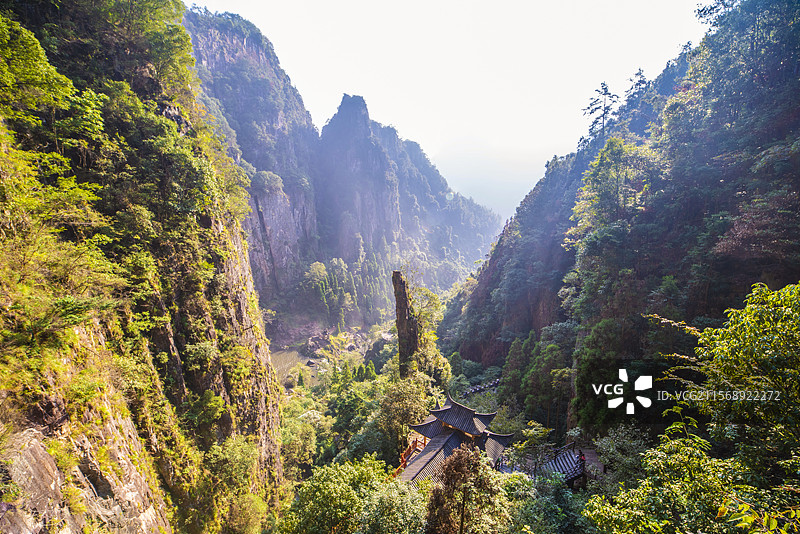温州文成百丈漈雾气弥漫的峡谷深涧中若隐若现的古屋脊前挺立的一根香形的敬天柱图片素材