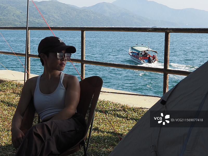 坐在靠海边的椅子上的人的后视图图片素材