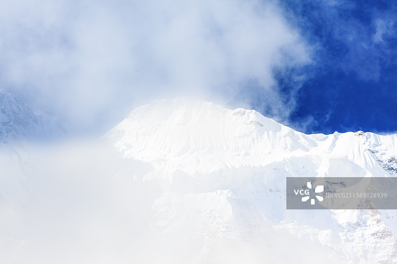 中国四川省甘孜州稻城亚丁白云下雪山山峰特写图片素材