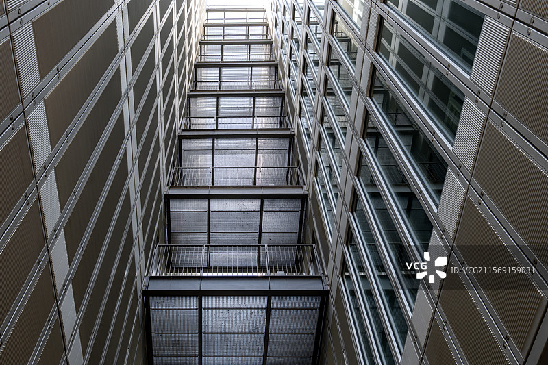 金属走廊穿插玻璃立面间的高楼仰视图片素材